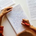 Student writing in notebook during an IELTS lesson