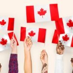 hands with canadian flags being held up by students who moved to canada after passing the IELTS test