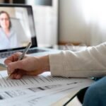 student having IELTS lessons with an instructor online and taking notes as she listens to instructions